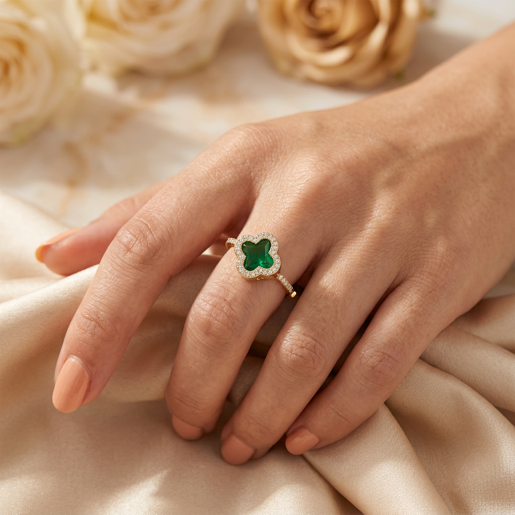 Cloverelle green quatrefoil ring worn on an adult hand gently gathering champagne satin