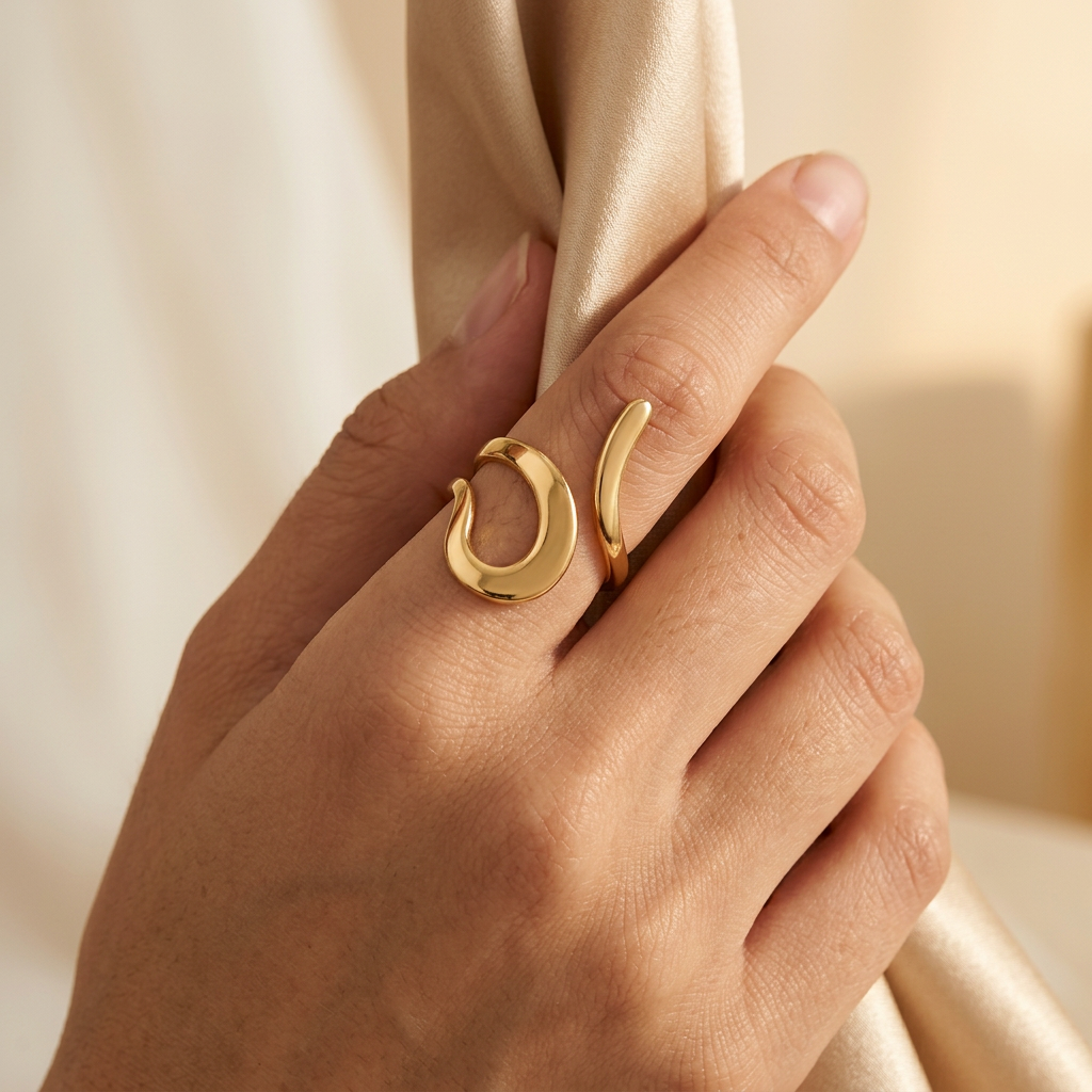 Adult model wearing gold-tone curl ring while gently holding champagne satin.