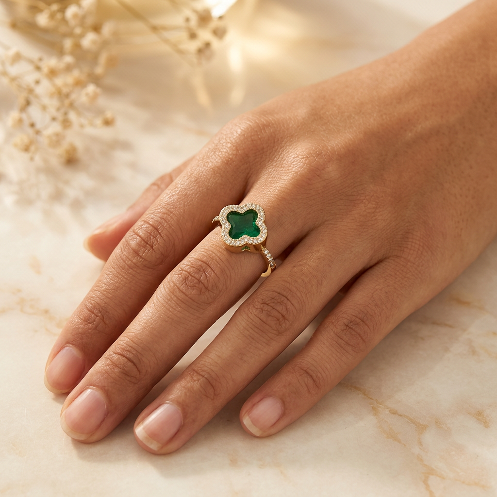 Cloverelle green quatrefoil halo ring worn on an adult hand resting on cream marble