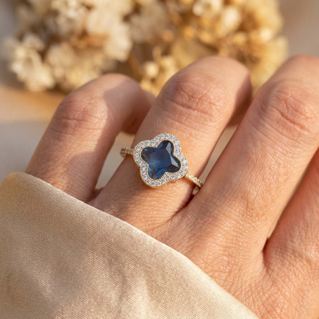 Adult hand wearing a blue quatrefoil halo ring while gathering champagne satin.
