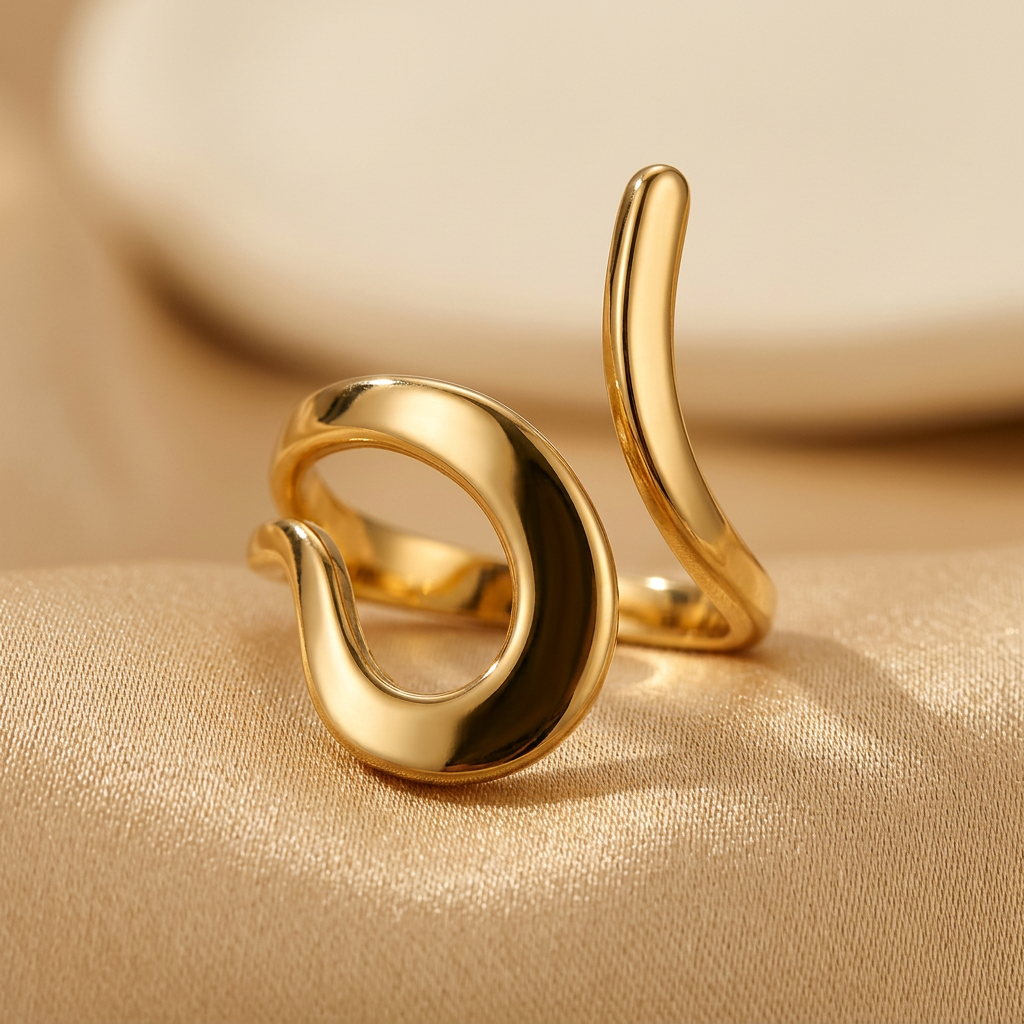 Close-up of gold-tone C-shaped curl and elongated end on champagne fabric.