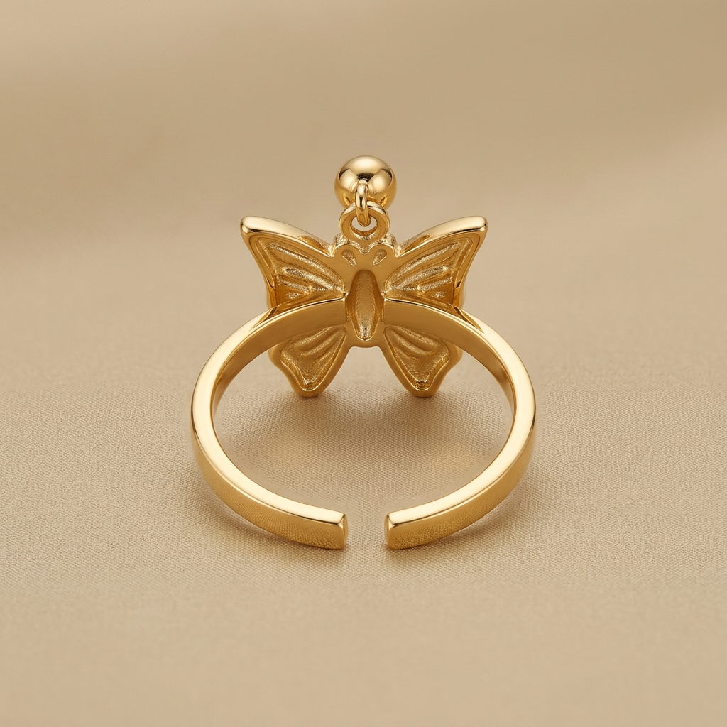 Rear detail of gold-tone butterfly ring showing separated band ends opposite the butterfly on champagne fabric.