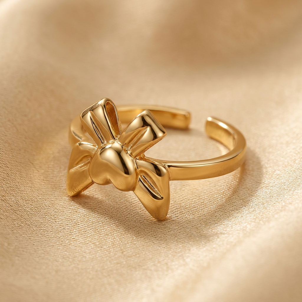 Close-up of gold-tone bow-inspired ring and open band against champagne gold.