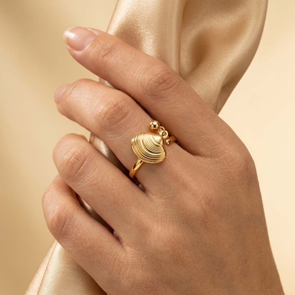 Adult model wearing gold-tone shell ring while gently holding champagne satin.