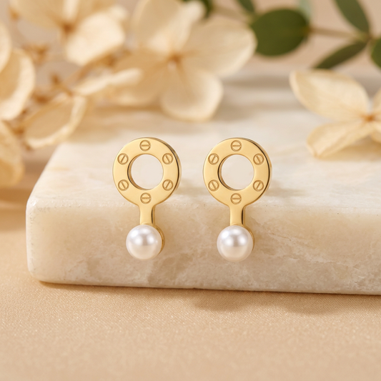 Orlina gold-tone circle pearl-look drop earrings arranged on cream marble