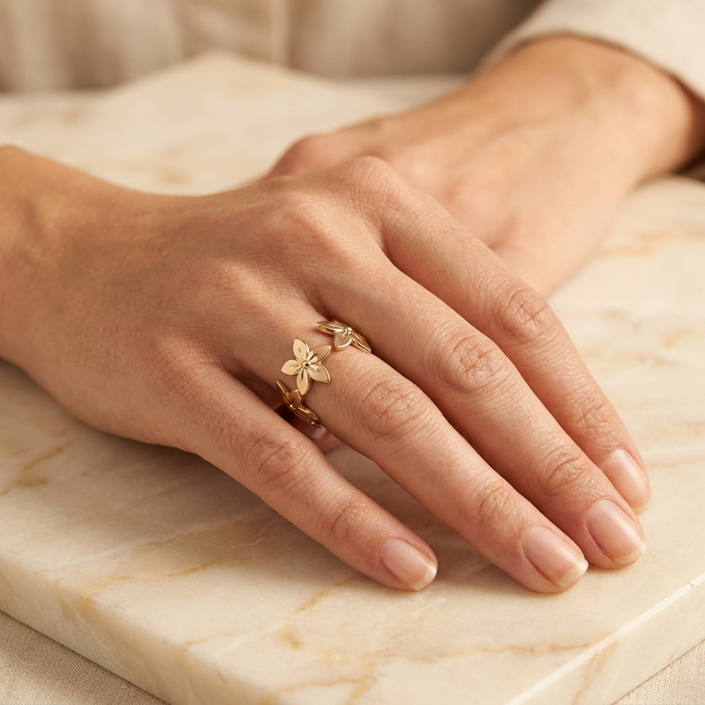 Adult model wearing gold-tone flower ring with hand resting on cream marble.